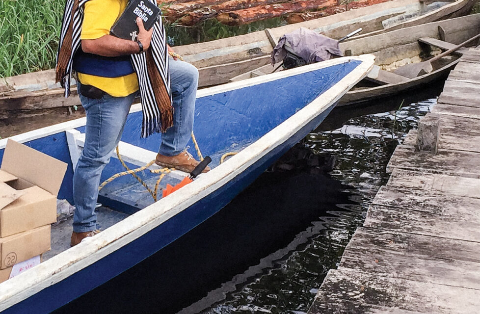 Man standing on a small boat holding a bible