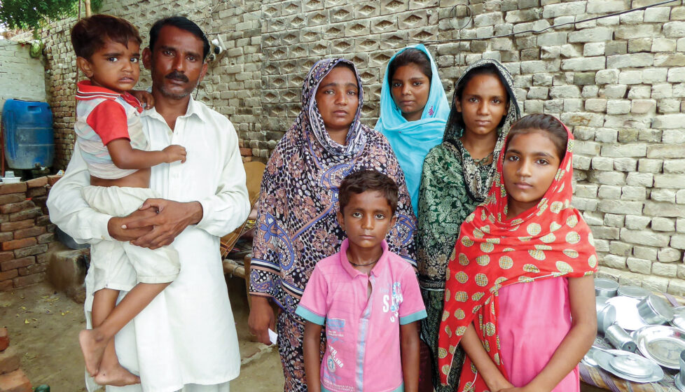 Central Asian family stands in front of wall
