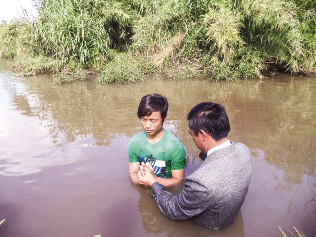 pastor baptizes a boy in the river
