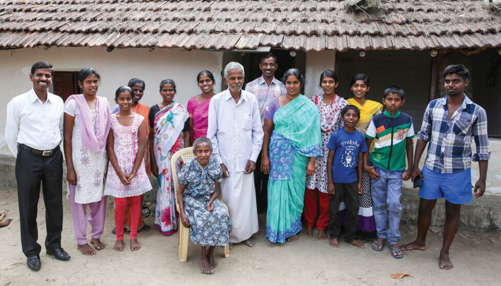 A large family stands together outside of their house